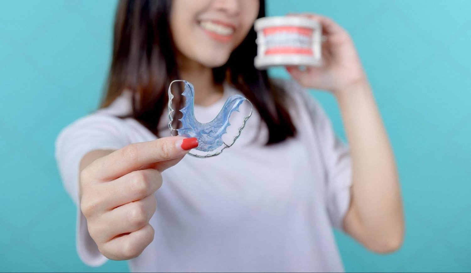 Patient in Abu Dhabi holding an Invisalign clear aligner and its storage case